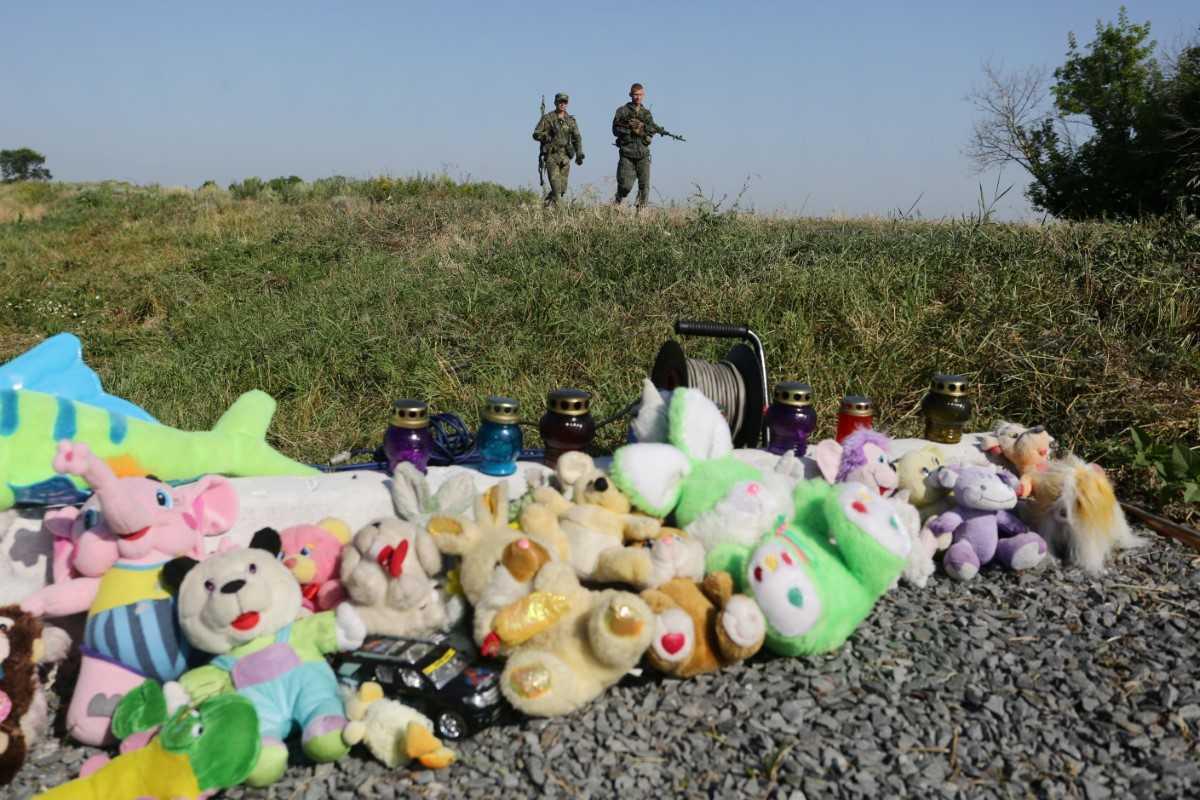 Pro-Russia armed rebels walk near stuffed animals and candles left at the site of the MH17 flight crash near Grabove village, Donetsk region, on July 17, 2016. Photo: AFP