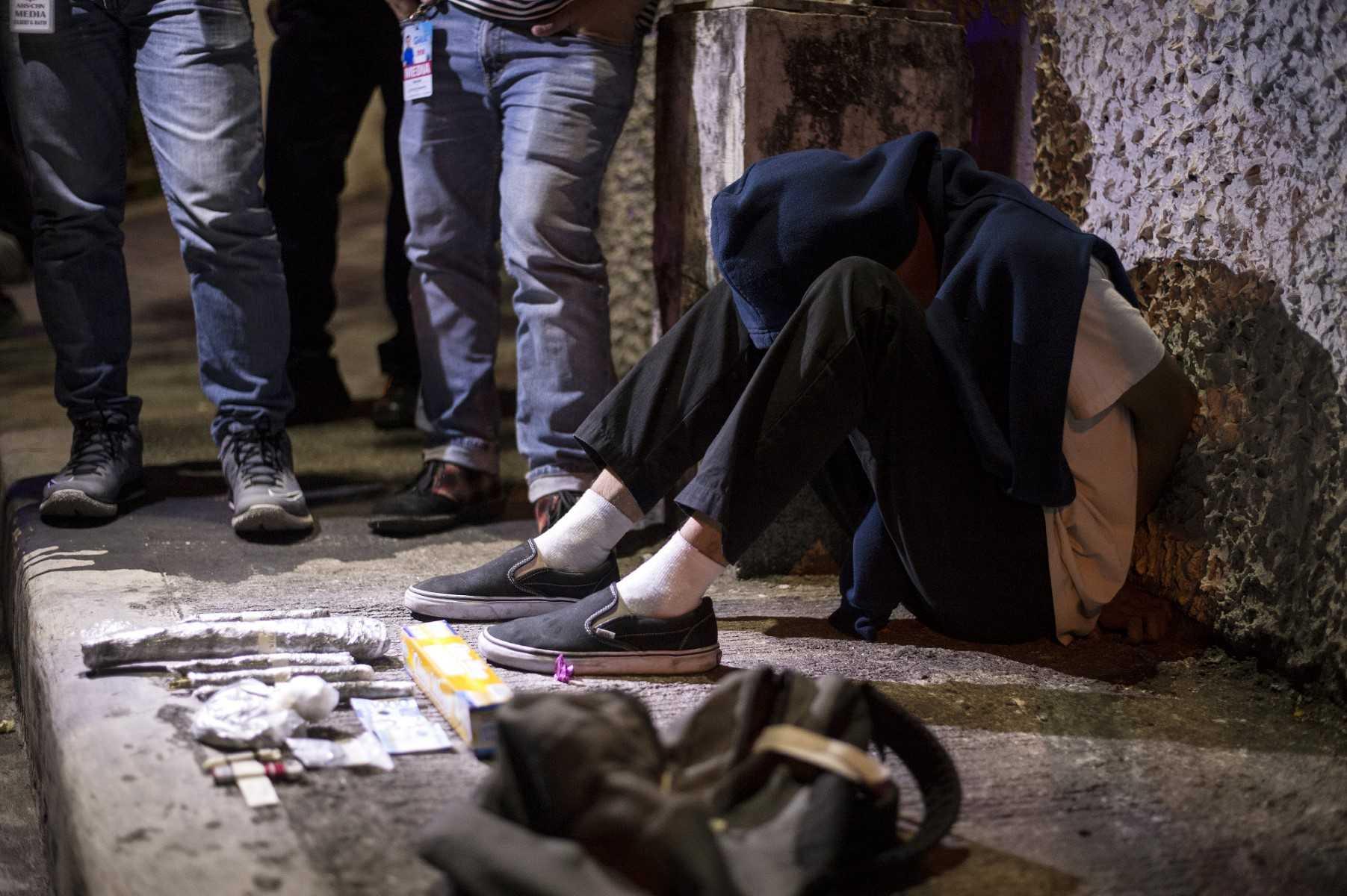 An alleged drug dealer is handcuffed after a drug bust operation conducted by policemen in Manila on May 12, 2018. Photo: AFP