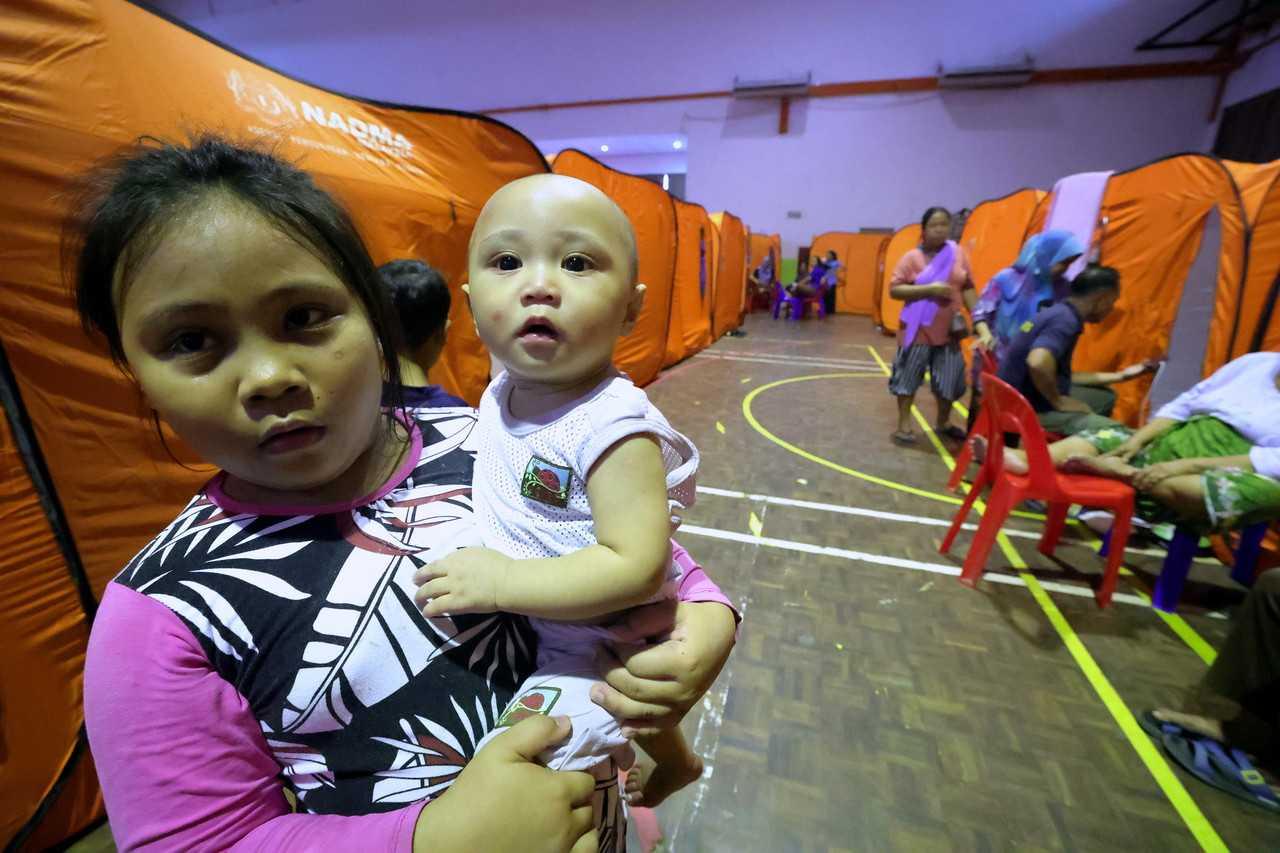 A young girl carries her baby brother at a flood relief centre in Kota Marudu, Sabah. Photo: Bernama