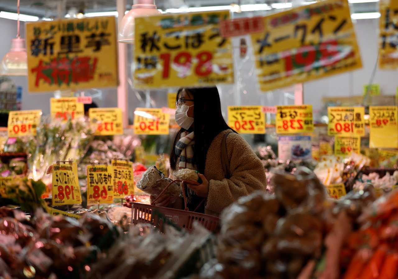 A woman wearing a face mask checks food items at a supermarket in Tokyo, Japan, Jan 20. Photo: Reuters