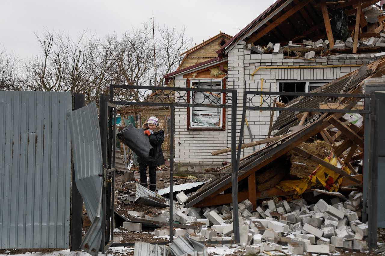 A resident removes debris from her neighbour's house, damaged by a Russian military strike amid Russia's attack on Ukraine, in the town of Hlevakha, outside Kyiv, Jan 26. Photo: Reuters