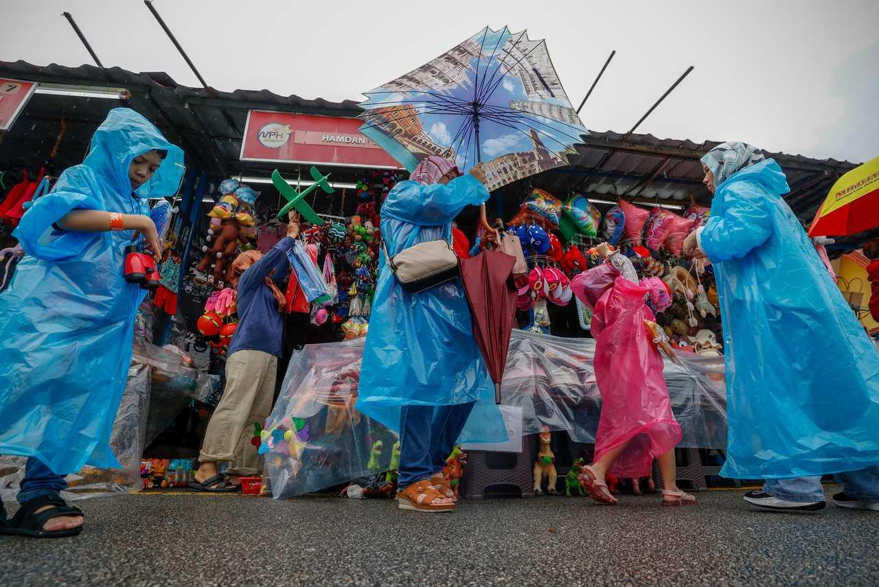 Visitors wearing raincoats make their way through Zoo Melaka. Photo: Bernama