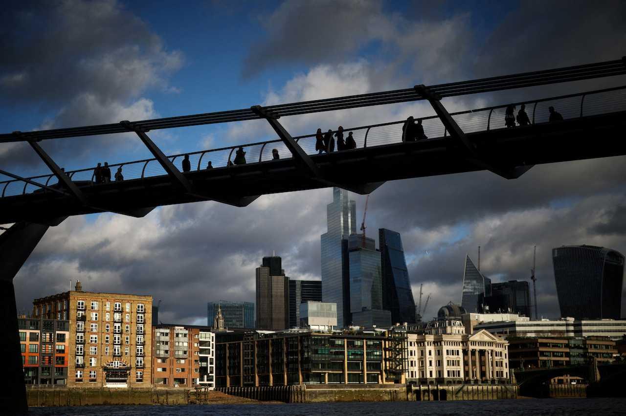 People walk over the Millennium Bridge with the London financial district in the background, in London, Britain, Jan 13. Photo: Reuters