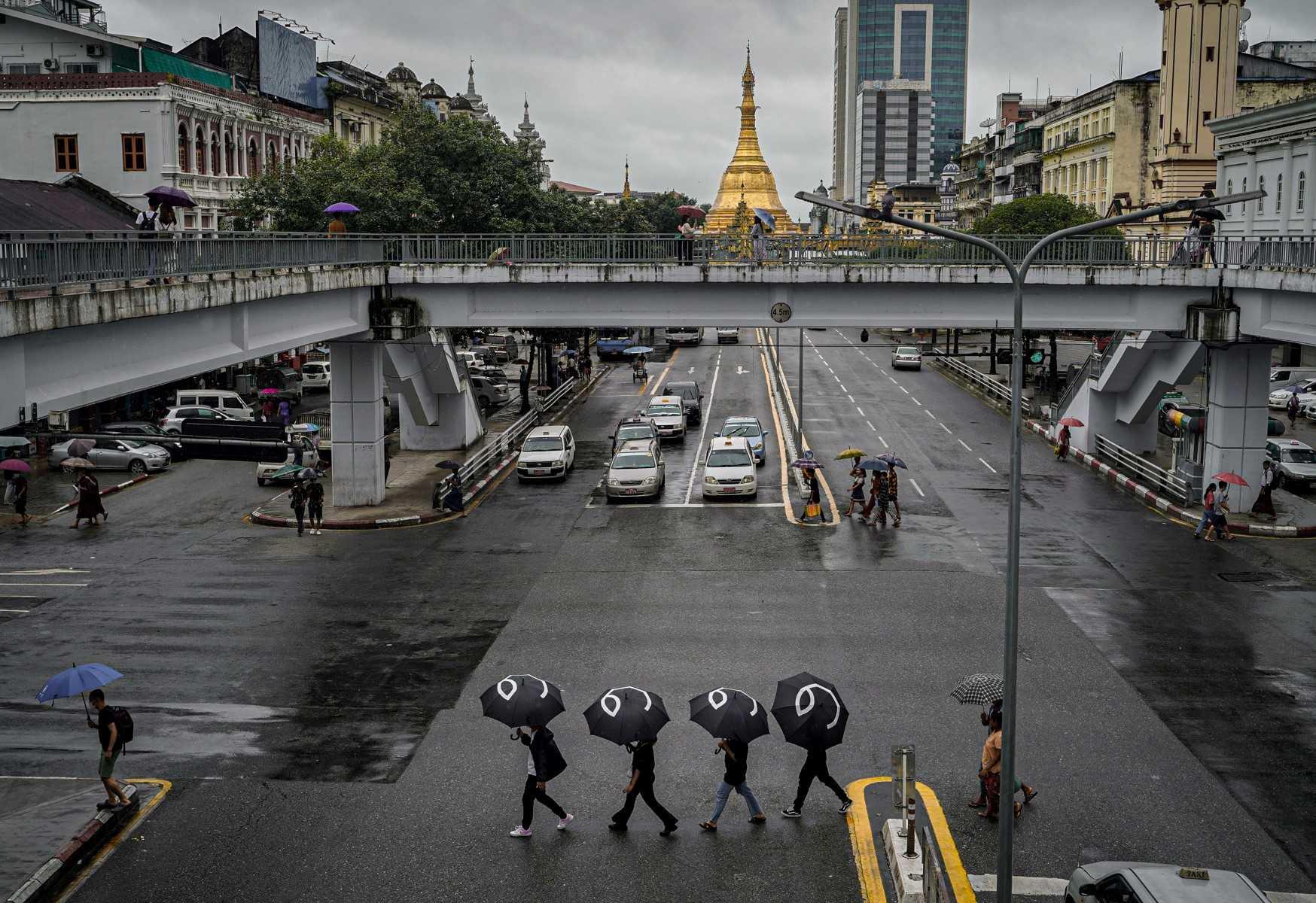 Gambar ini diambil pada 8 Ogos 2022, menujukkan penunjuk perasaan berjalan mengeliling Yangon dengan membawa payung tertera angka lapan. Gambar: AFP