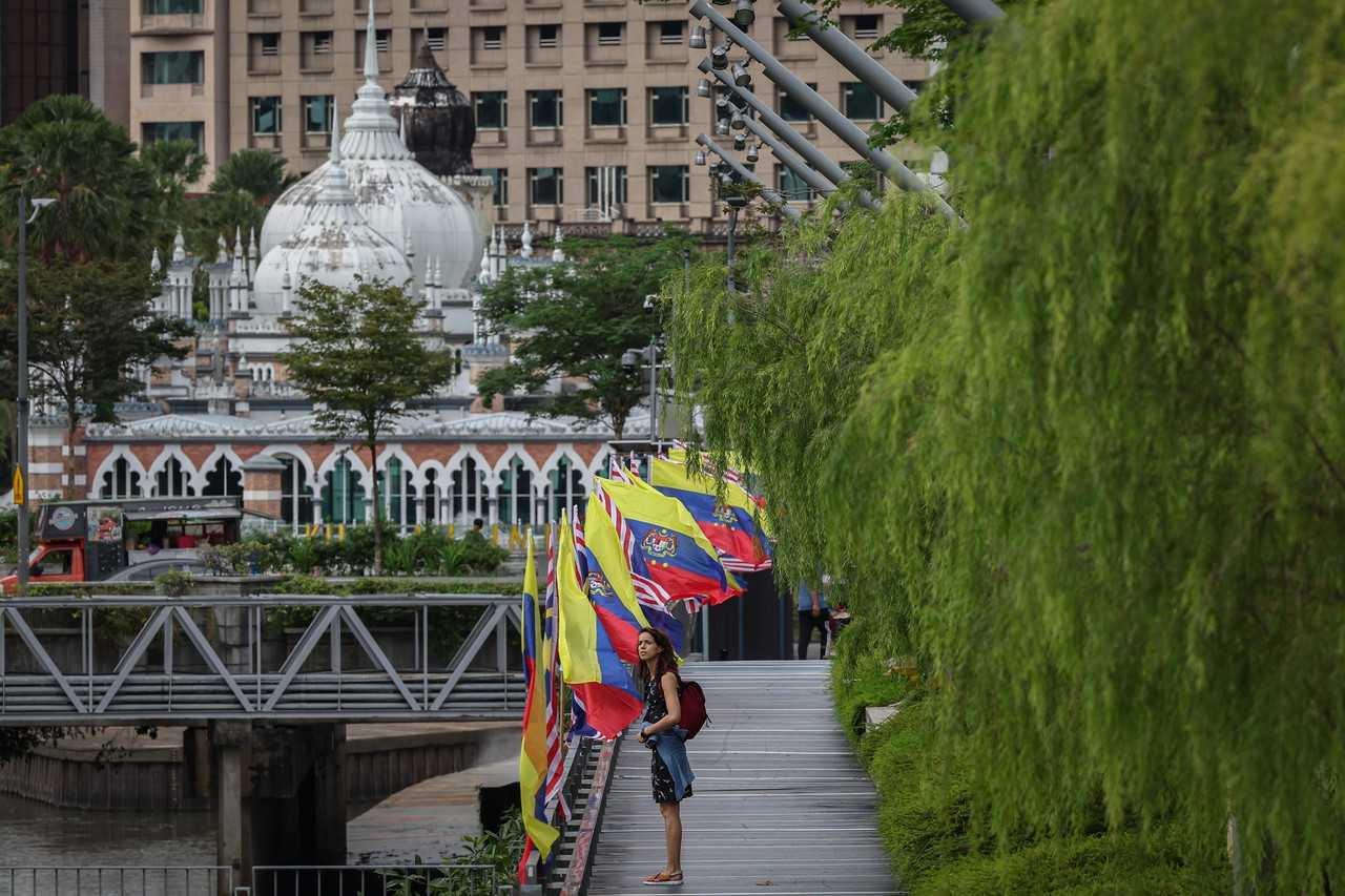 A tourist stands beneath a row of flags, ahead of Federal Territories Day at the River of Life in Jalan Benteng, Kuala Lumpur. Photo: Bernama