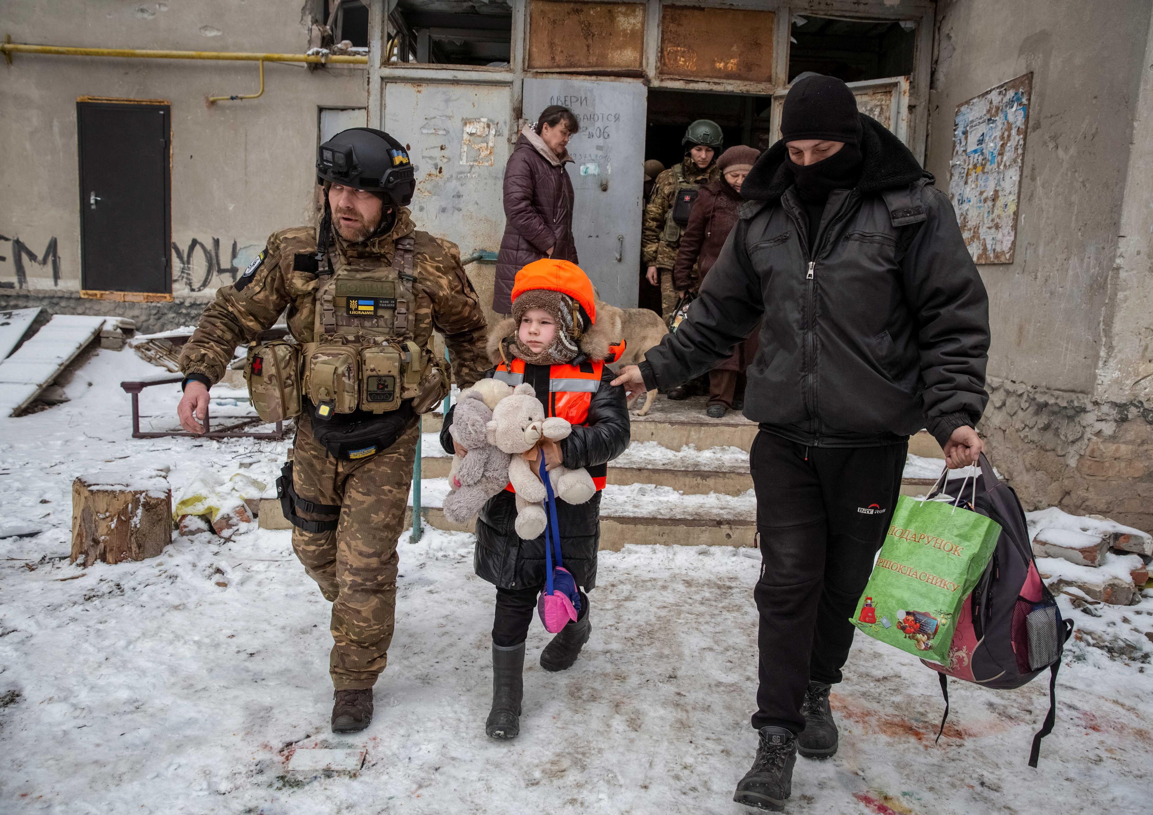 Policemen help a girl dressed in children's bulletproof vest and helmet during her evacuation from front line city of Bakhmut, amid Russia's attack on Ukraine, in Donetsk region, Ukraine Jan 31. Photo: Reuters