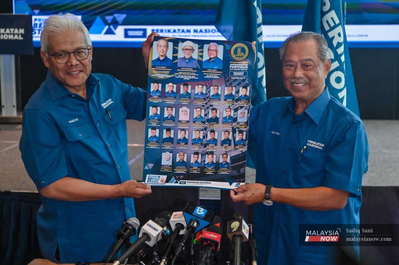 Perikatan Nasional chairman Muhyiddin Yassin (right) holds up a chart showing the coalition's shadow Cabinet with opposition leader Hamzah Zainudin in Kuala Lumpur, Feb 2. 
