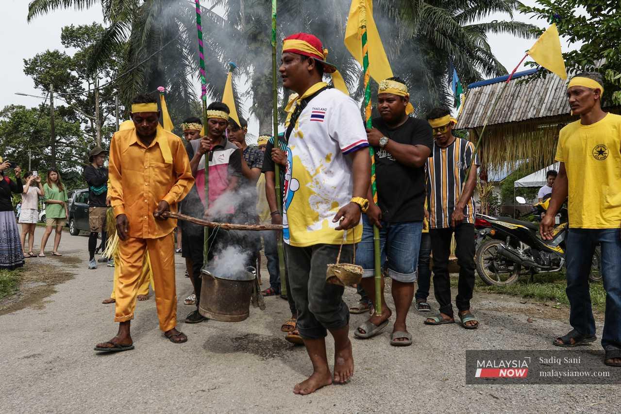 Outside, other villagers carry flags and utensils to be used during the ritual. 
