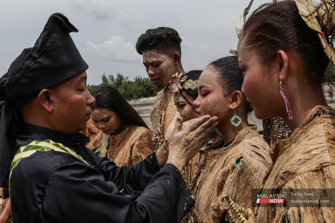 Another smears rice powder on the faces of young girls as part of the ritual. 