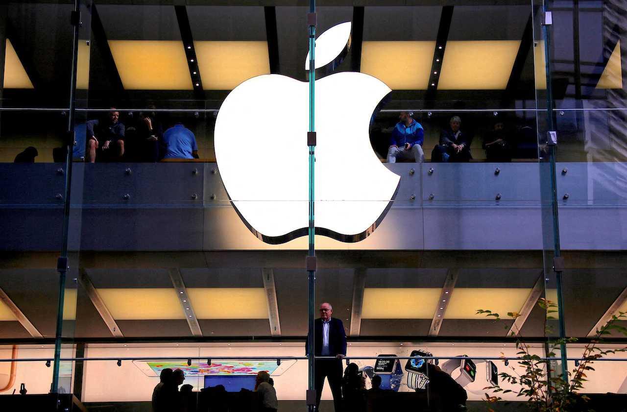 A customer stands underneath an illuminated Apple logo as he looks out the window of the Apple store located in central Sydney, Australia, May 28, 2018. Photo: Reuters