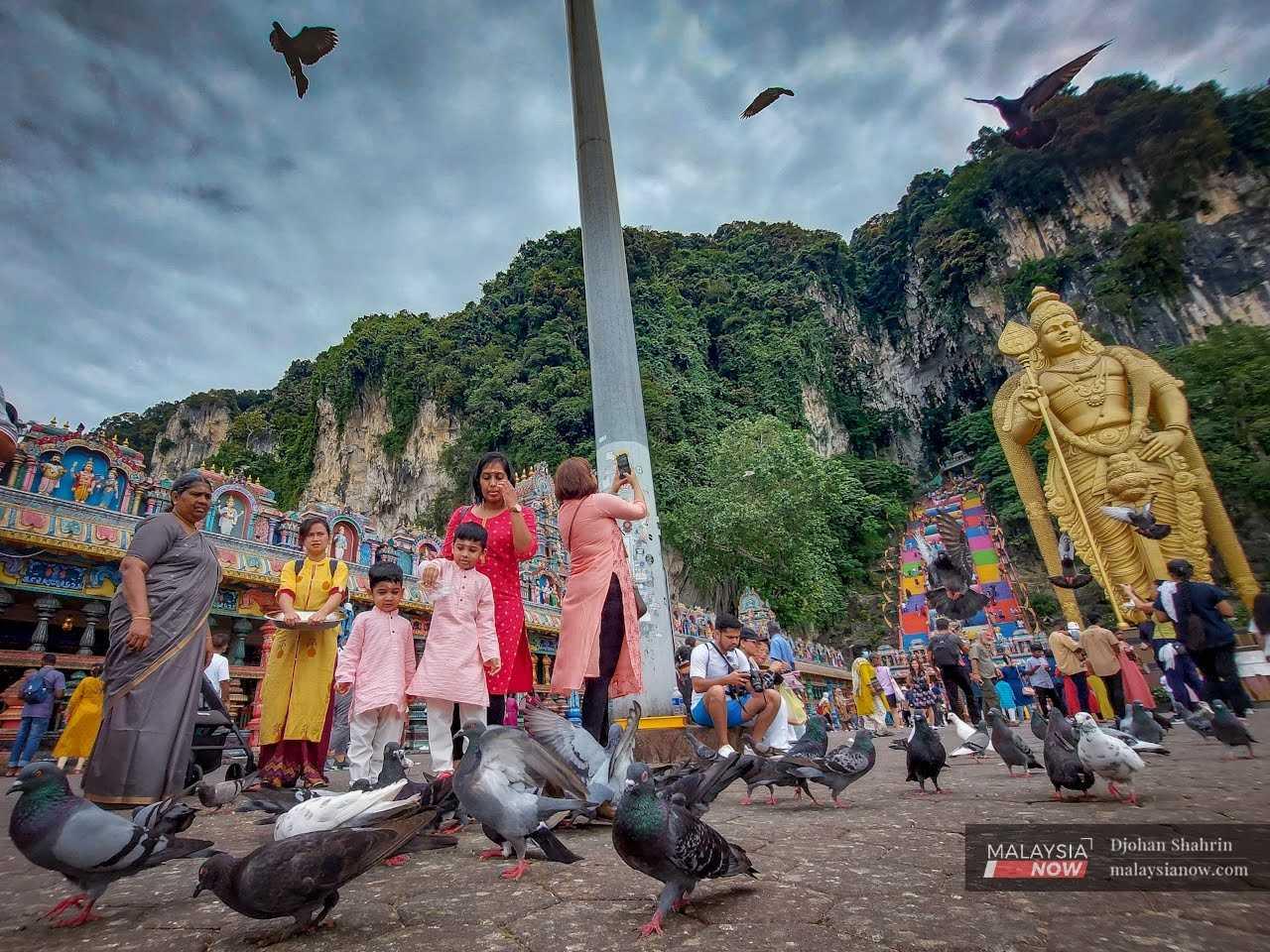 Dua kanak-kanak memberi makan kepada sekumpulan burung merpati sewaktu hadir ke kuil di Batu Caves bagi mengikuti upacara keagamaan sempena meraikan Hari Thaipusam yang akan disambut Ahad ini, 2 Februari.