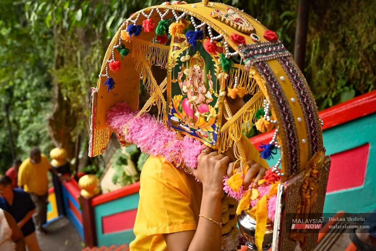 A woman carries a kavadi on her shoulder as she goes up the stairs. 