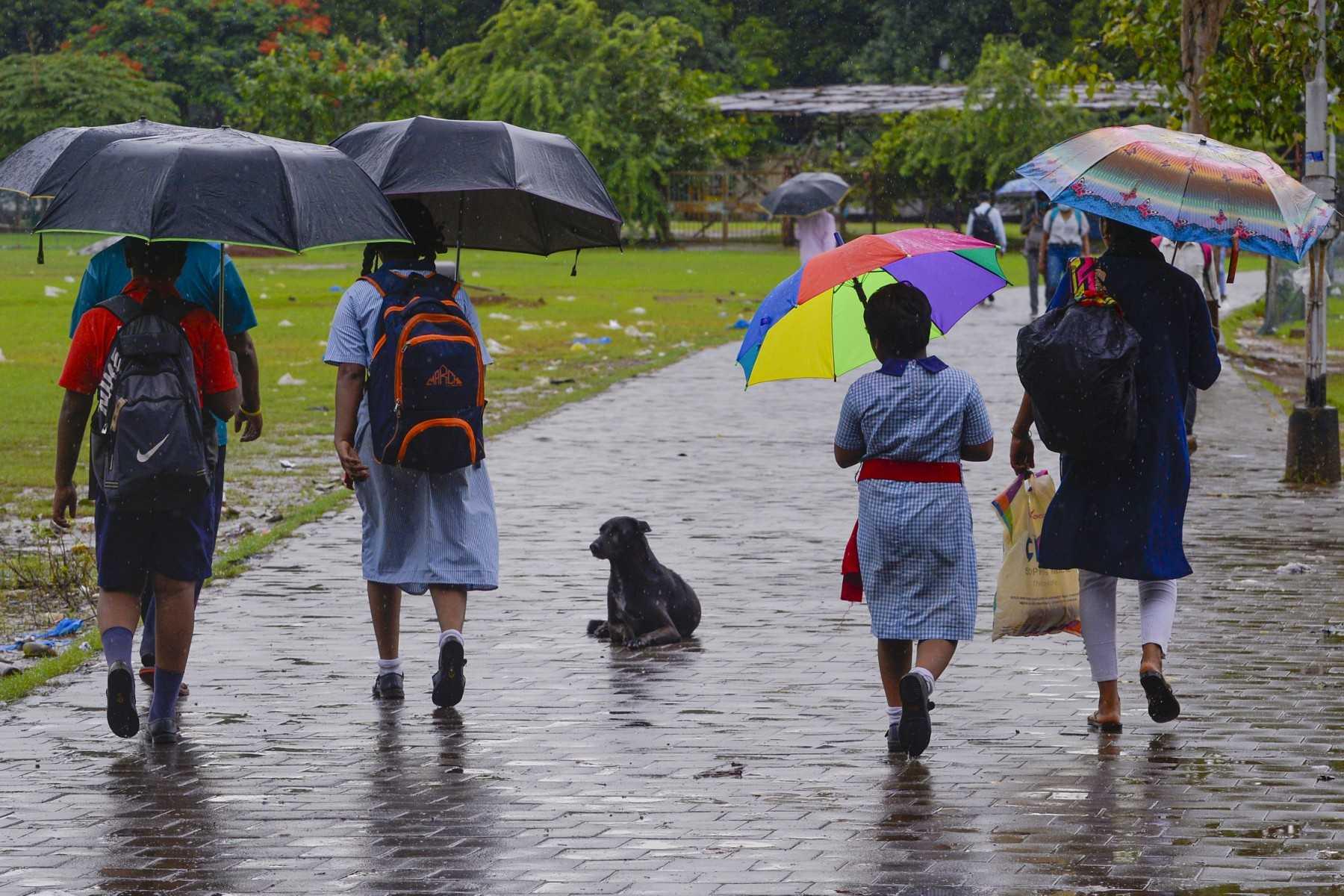 Guardians walk children to school amid rain in Mumbai on June 22, 2022. The legal marriage age in India is 18 but millions of children are forced to tie the knot when they are younger, particularly in poorer rural areas. Photo: AFP
