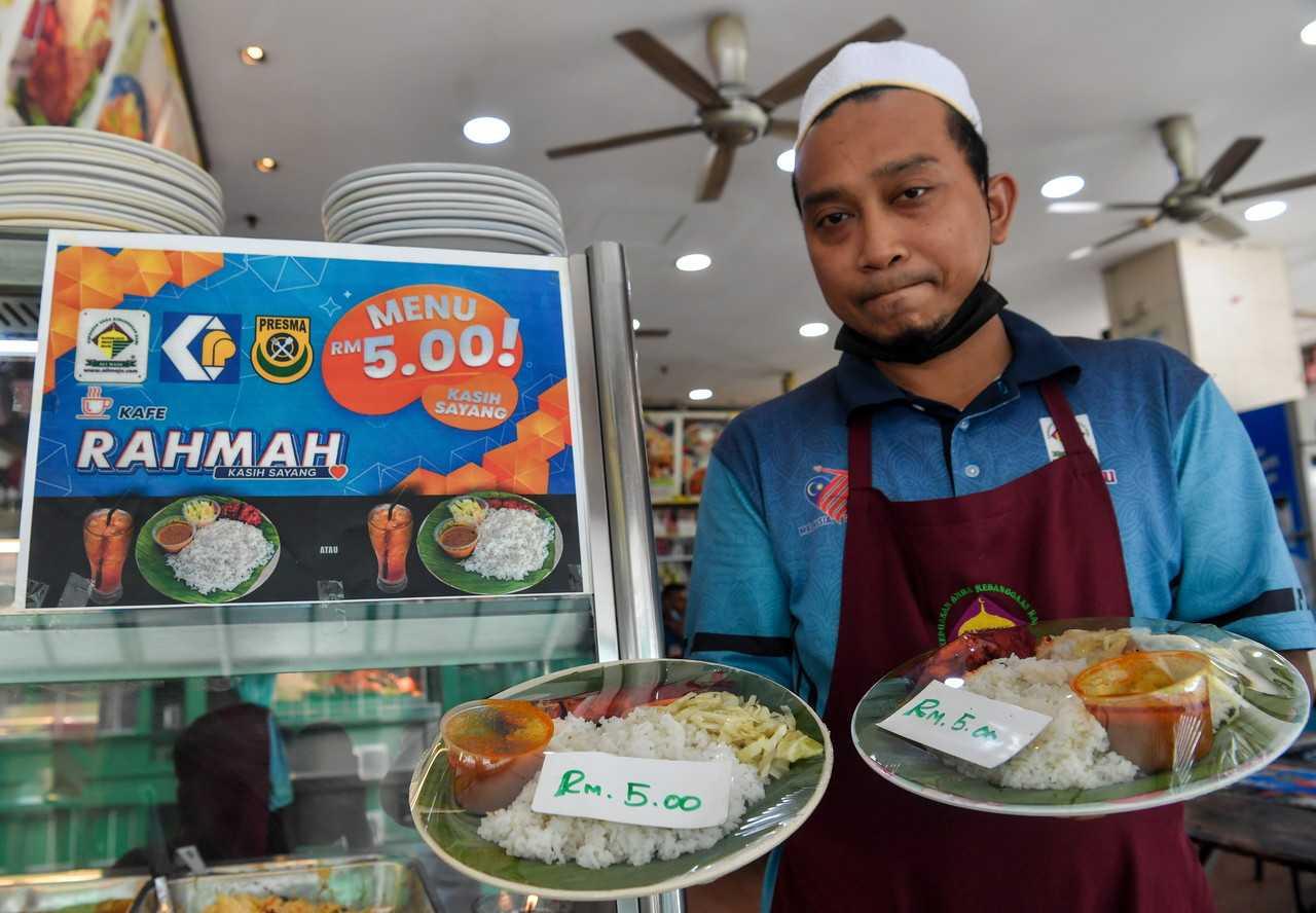 Pekerja restoran menunjukkan contoh makanan yang ditawarkan di bawah program Menu Rahmah di Kuala Lumpur.