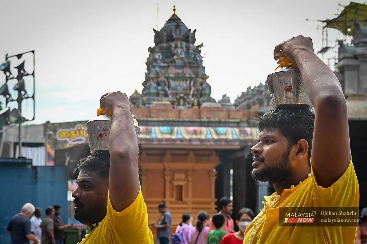 Hindu devotees carry pots of fresh milk on their heads as they prepare to participate in a religious ceremony at the iconic temple in Batu Caves, Selangor.