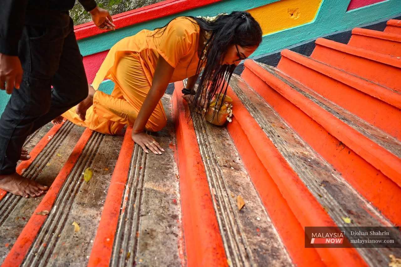 A young woman crawls up the steps in a show of devotion.