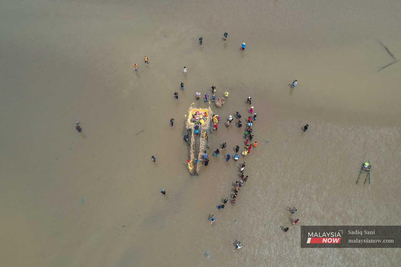 Penduduk kampung berkumpul mengelilingi ‘mahligai’ yang diletakkan di tengah-tengah pantai ketika upacara bermula.