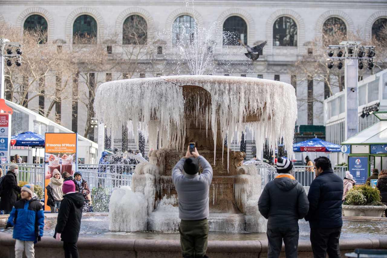 People take a selfie in front of a mostly frozen fountain in Manhattan, as deep cold spreads across the northeast US in New York City, Feb 4. Photo: Reuters