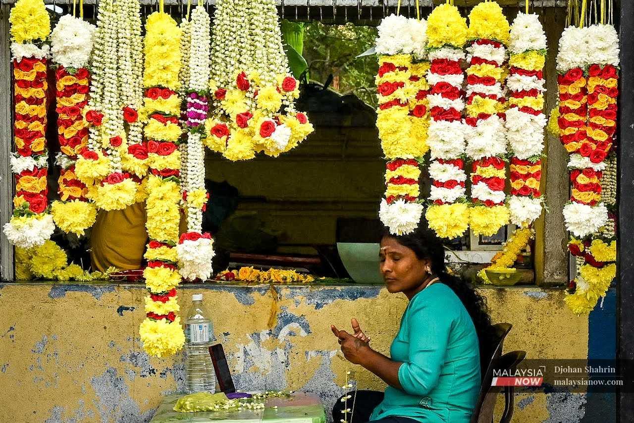 Seorang wanita mengikat kalungan bunga malai untuk dijual kepada penganut Hindu yang akan digunakan sewaktu perayaan Thaipusam.
