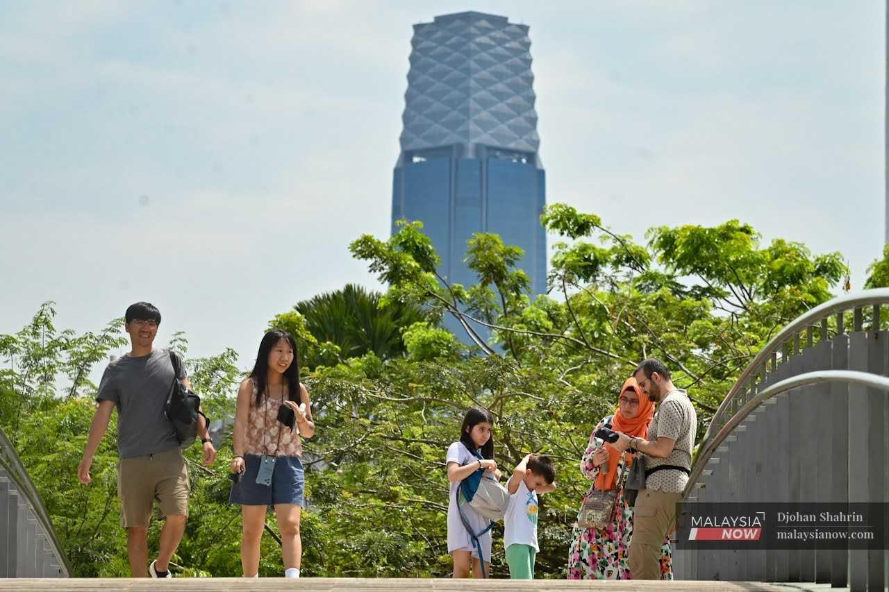Pelancong asing dan tempatan bergambar di sekitar ‘River of Life’, Kuala Lumpur sambil berlatar belakangkan menara Tun Razak Exchange, 1 Februari.