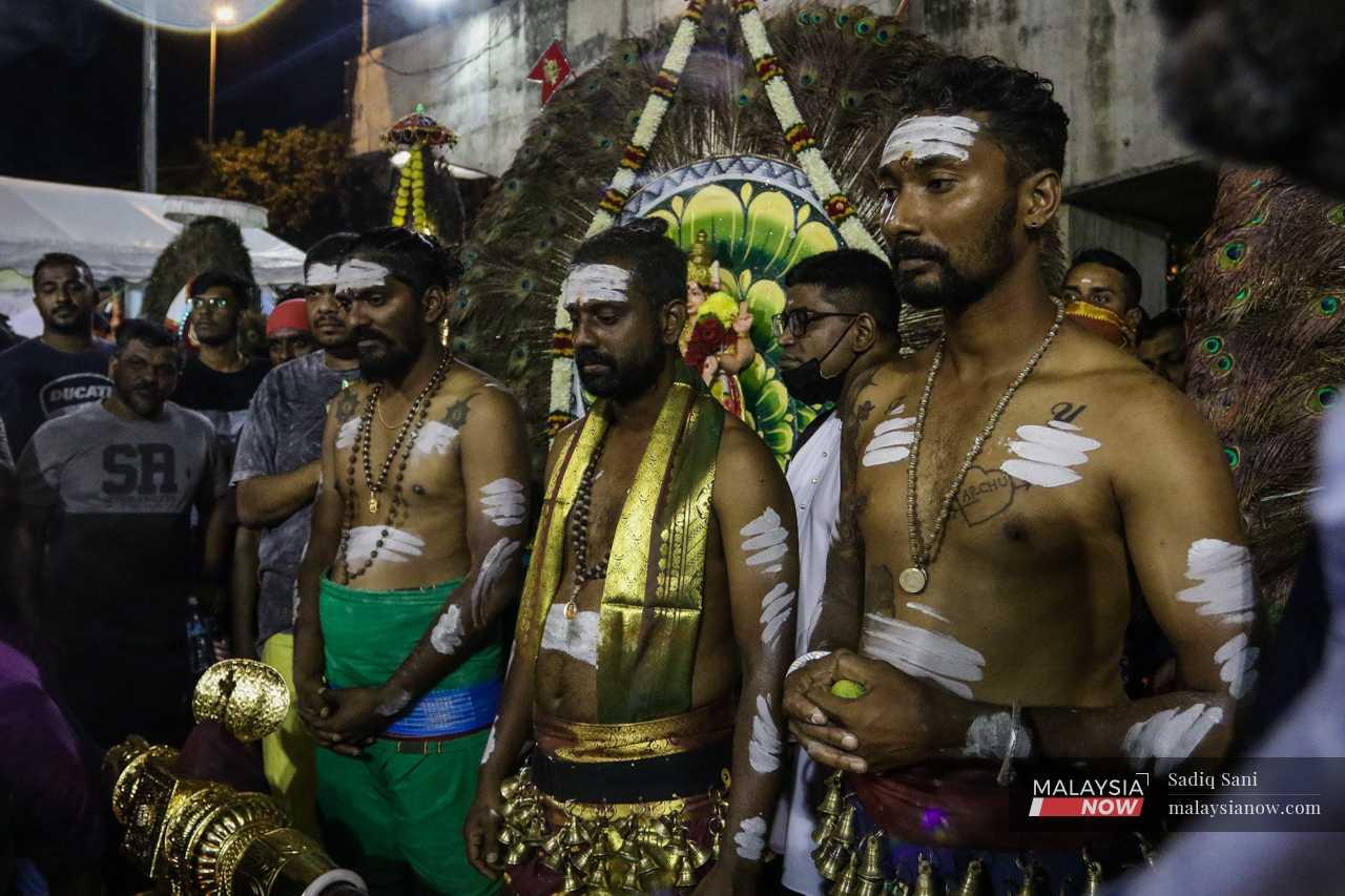 Suresh stands with his brothers, Krishna and Parthiban, as the priest says a prayer before the start of the procession. 