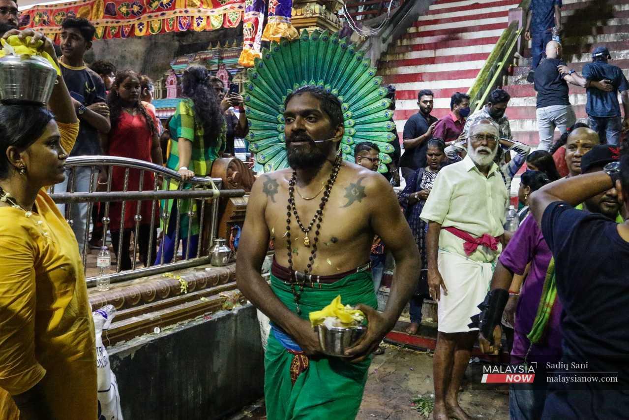 He puts down his kavadi and approaches the temple, carrying a pot of fresh milk to be used during the next ritual. 
