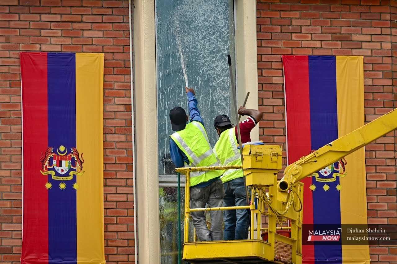 Dua pekerja kontrak melakukan kerja-kerja pembersihan di bahagian cermin Bangunan Perpustakaan Kuala Lumpur, 1 Februari.