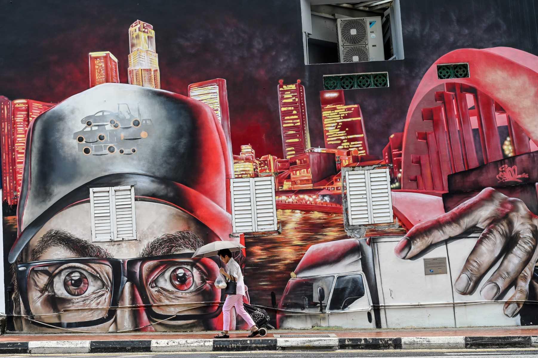 A woman walks past a wall mural on the side of a building at Boat Quay in Singapore on Oct 20, 2022. Photo: AFP