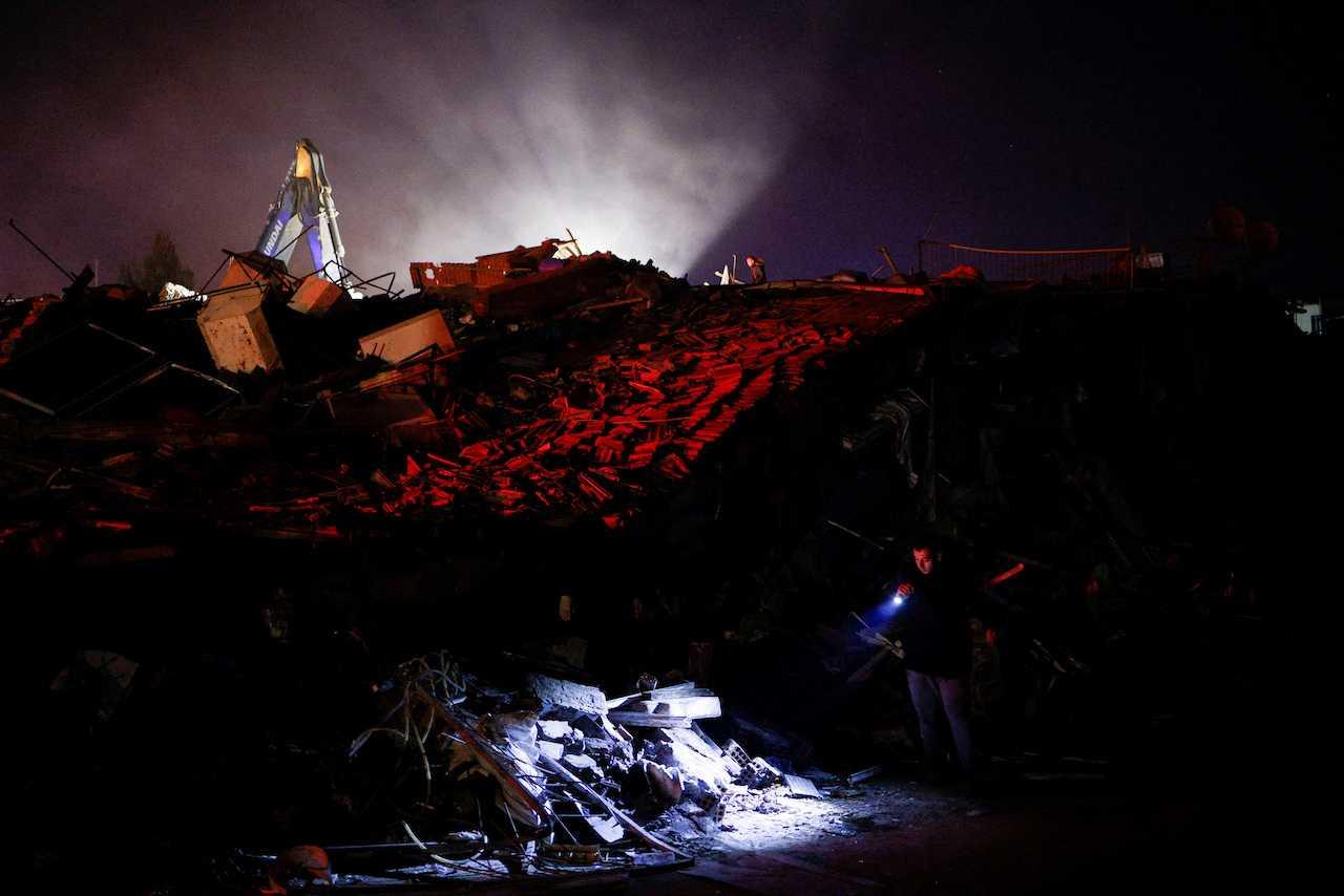 A man uses a lantern to check damaged buildings, in the aftermath of an earthquake, in Antakya, Turkey, Feb 8. Photo: Reuters