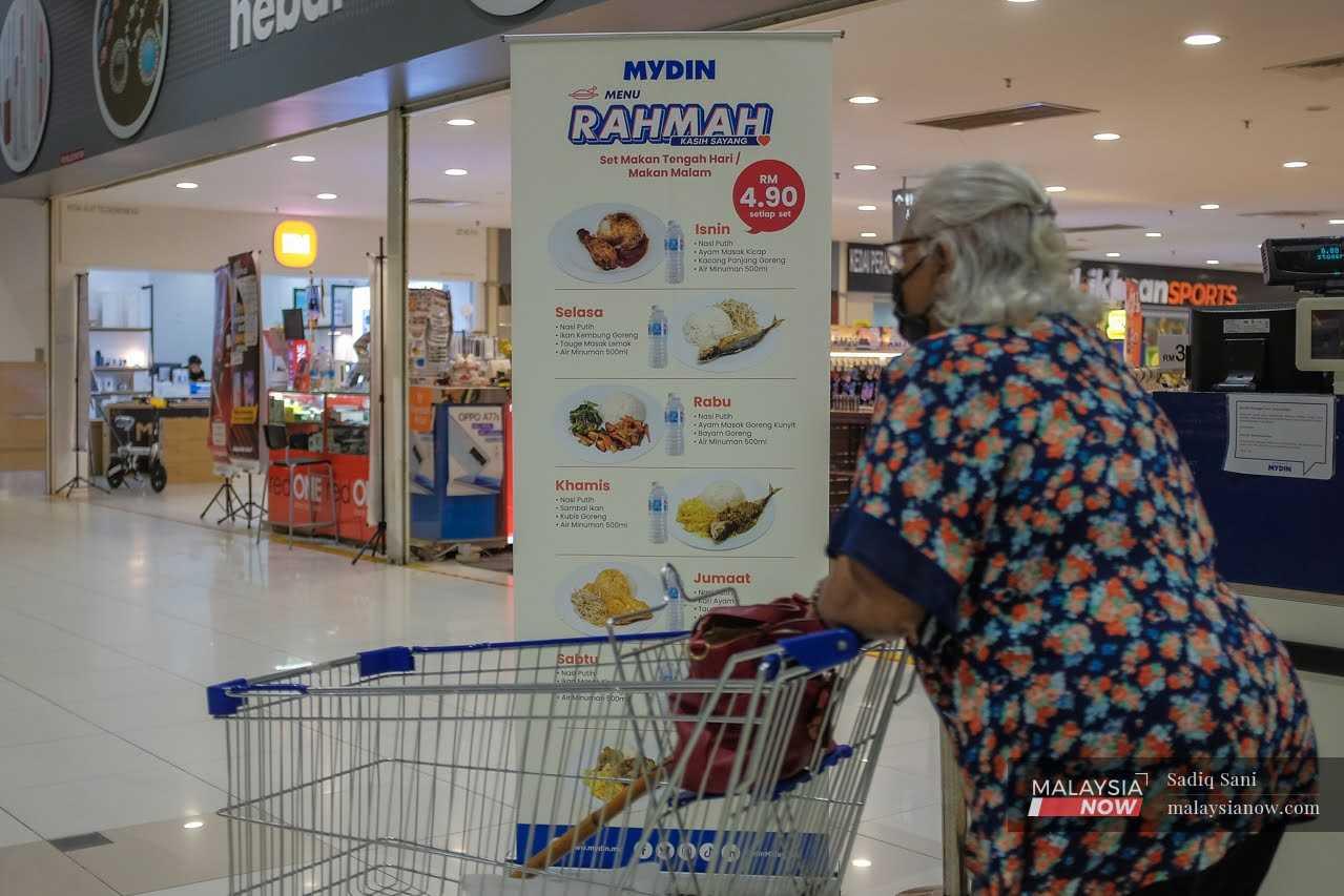 Seorang pelanggan berjalan melintasi poster Menu Rahmah di sebuah pasar raya di Subang, Selangor, 9 Februari.