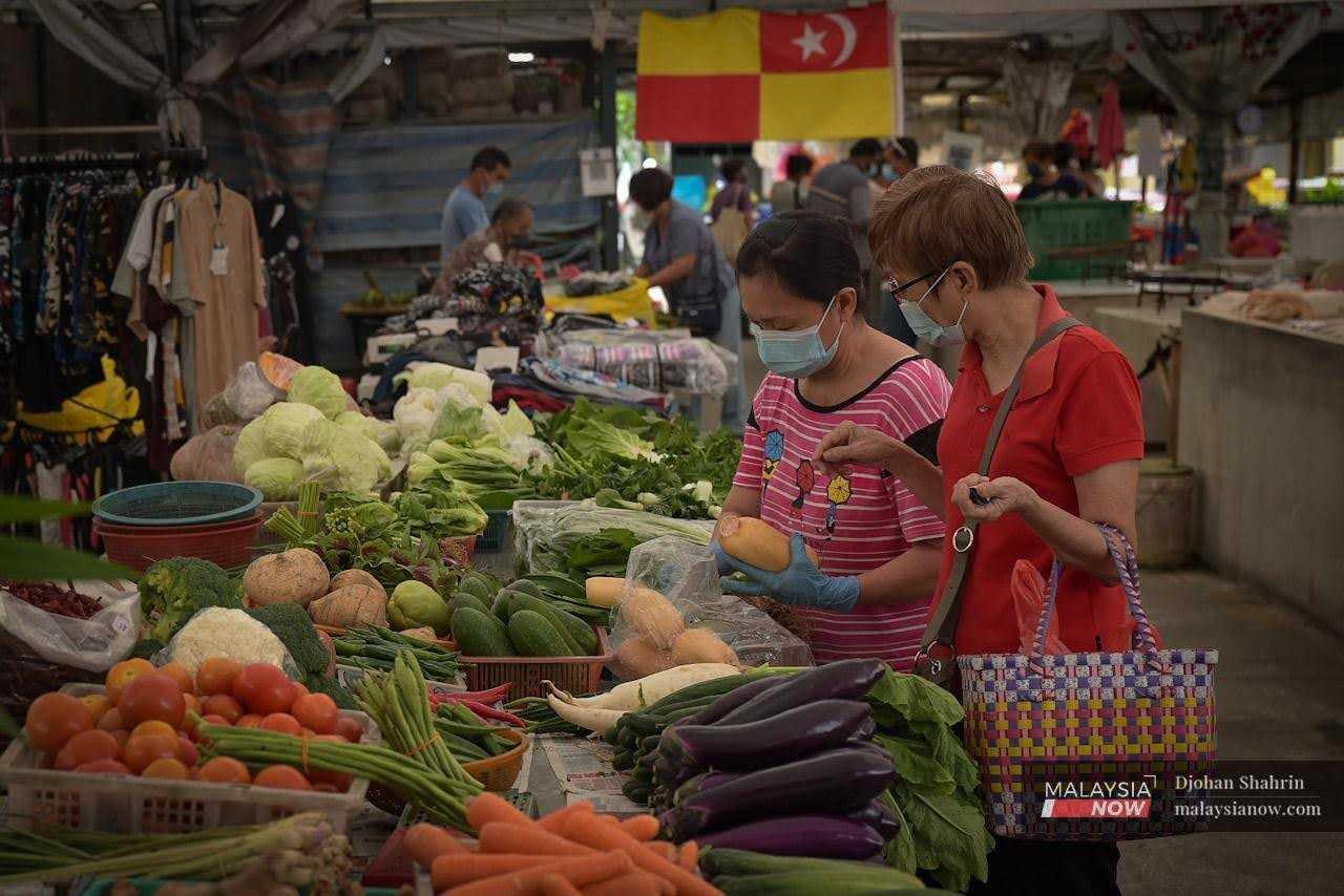 Seorang pelanggan membeli barang keperluan di bahagian jualan sayur di Pasar Ampang, Selangor.
