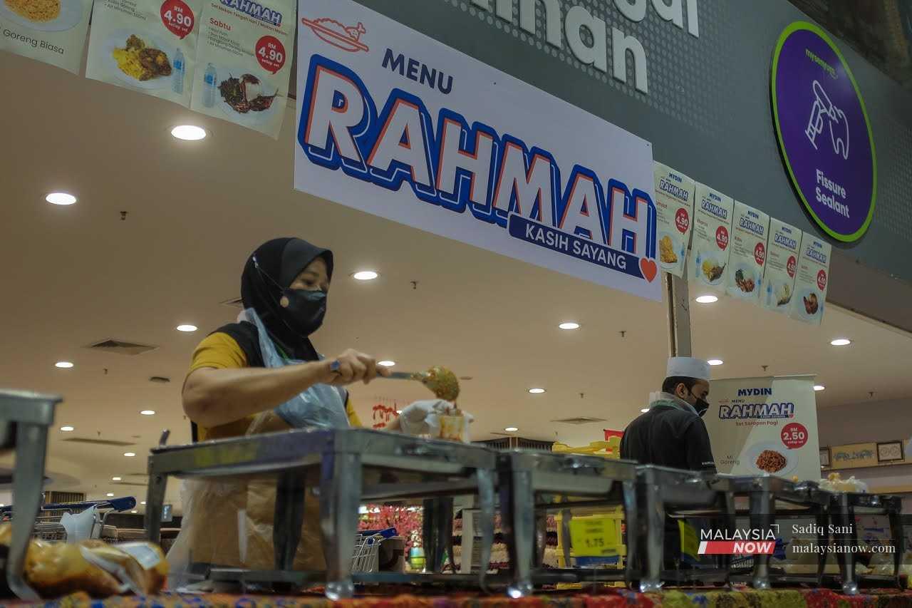 Seorang pekerja sedang membungkus makanan yang dijual pada harga RM5 di bawah program Menu Rahmah oleh Kementerian Perdagangan Dalam Negeri dan Kos Sara Hidup.