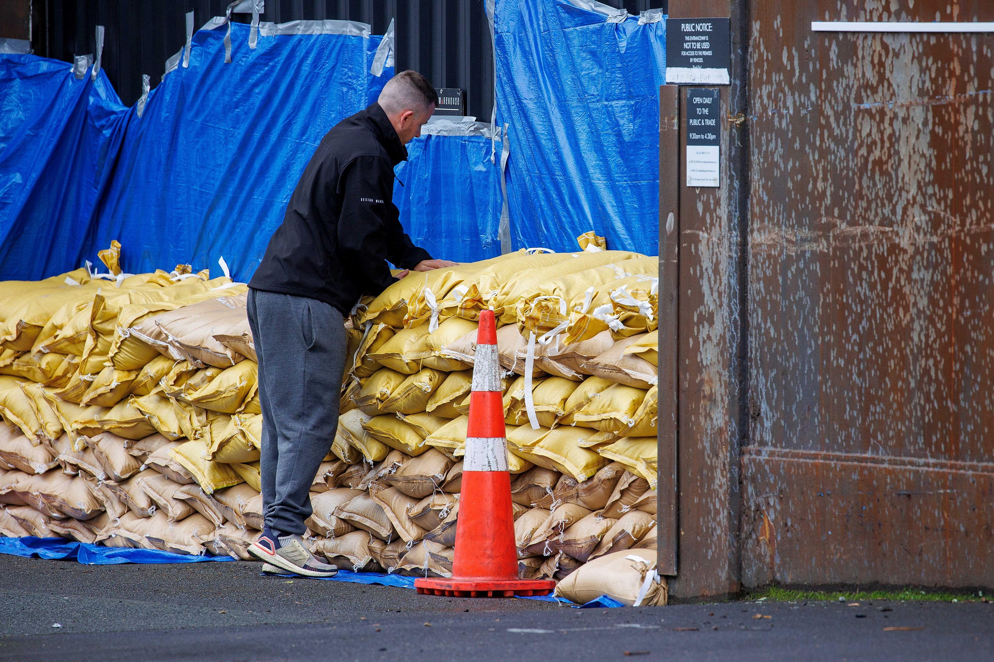 Seorang lelaki menyusun beg pasir untuk melindungi sebuah gudang sebagai persiapan sebelum Taufan Gabriele membadai Auckland, New Zealand, 12 Februari. Gambar: Reuters