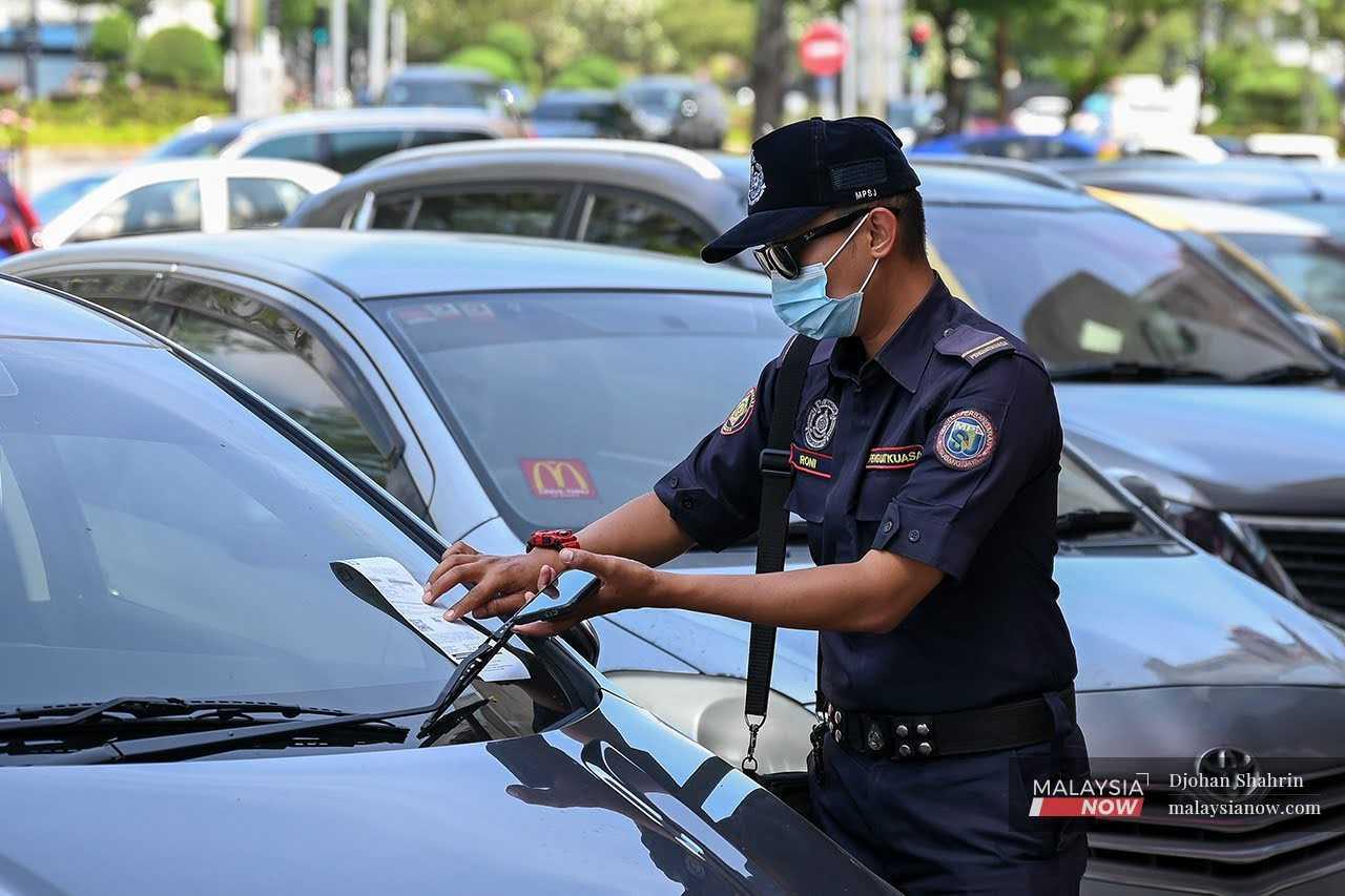 Seorang polis mengeluarkan saman di Subang, Selangor.