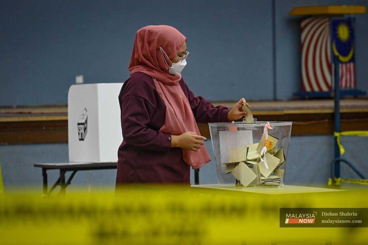 Seorang pengundi memasukkan kertas undi ke dalam peti yang disediakan selepas menjalankan tanggungjawab di Sekolah Kebangsaan Klang Gate, Hulu Kelang, 19 November 2022. 