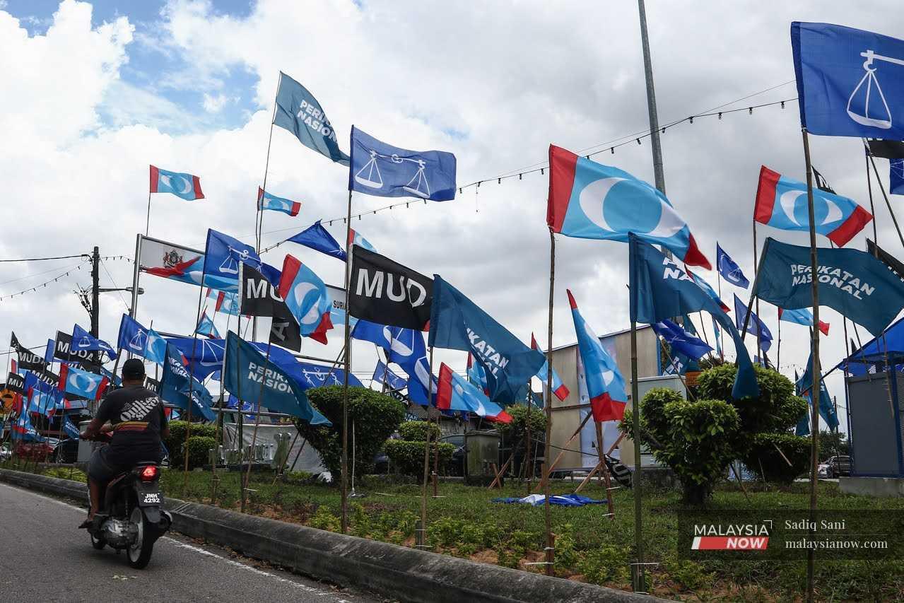 A motorcyclist rides past the party flags of PKR, Muda, Perikatan Nasional and Barisan Nasional at a junction near Kampung Melayu Majidee ahead of the Johor state election in March 2022.