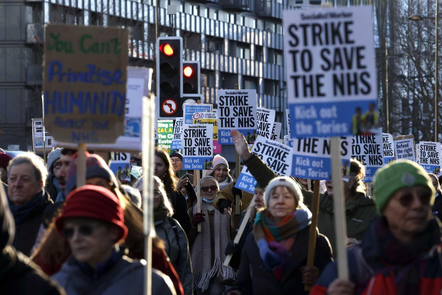 People hold placards as they take part in a protest march organised in London on Jan 18, in support of ongoing pay disputes. Photo: AFP