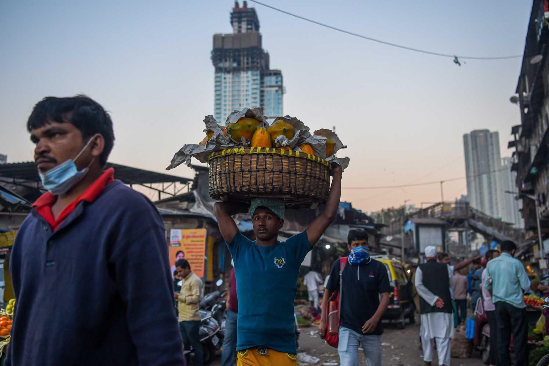 A daily wage worker carries a basket filled with fruits during early morning at a wholesale market in Mumbai on Feb 1. Photo: AFP 