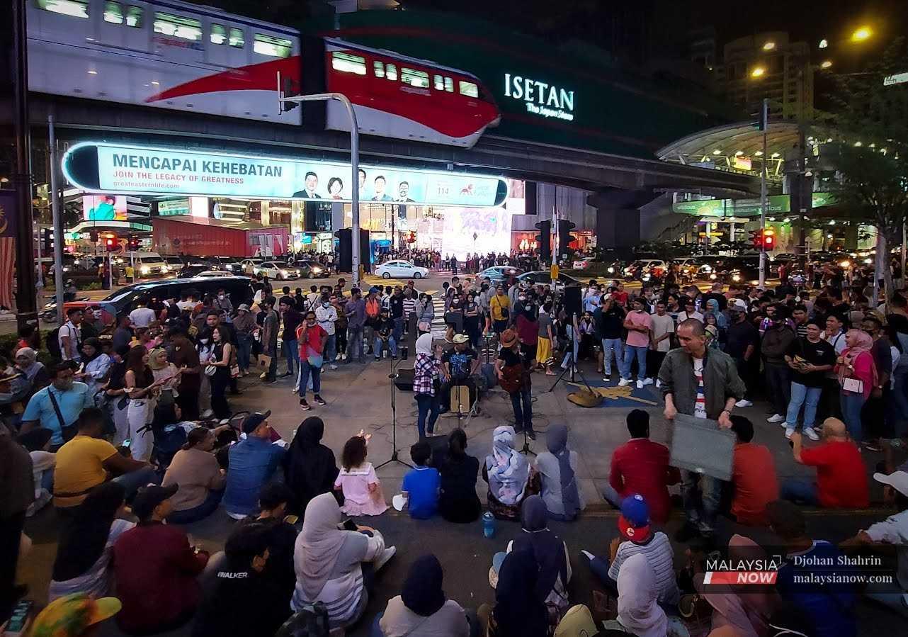 Orang ramai meluangkan masa melihat persembahan seniman jalanan pada malam Tahun Baru di Bukit Bintang, 31 Disember 2022.