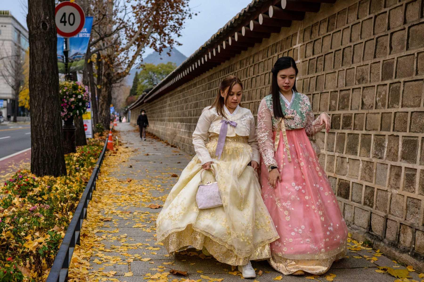 Beberapa wanita memakai pakaian tradisional Hanbok semasa berjalan ketika musim luruh di Seoul pada 21 November 2022. Gambar: AFP