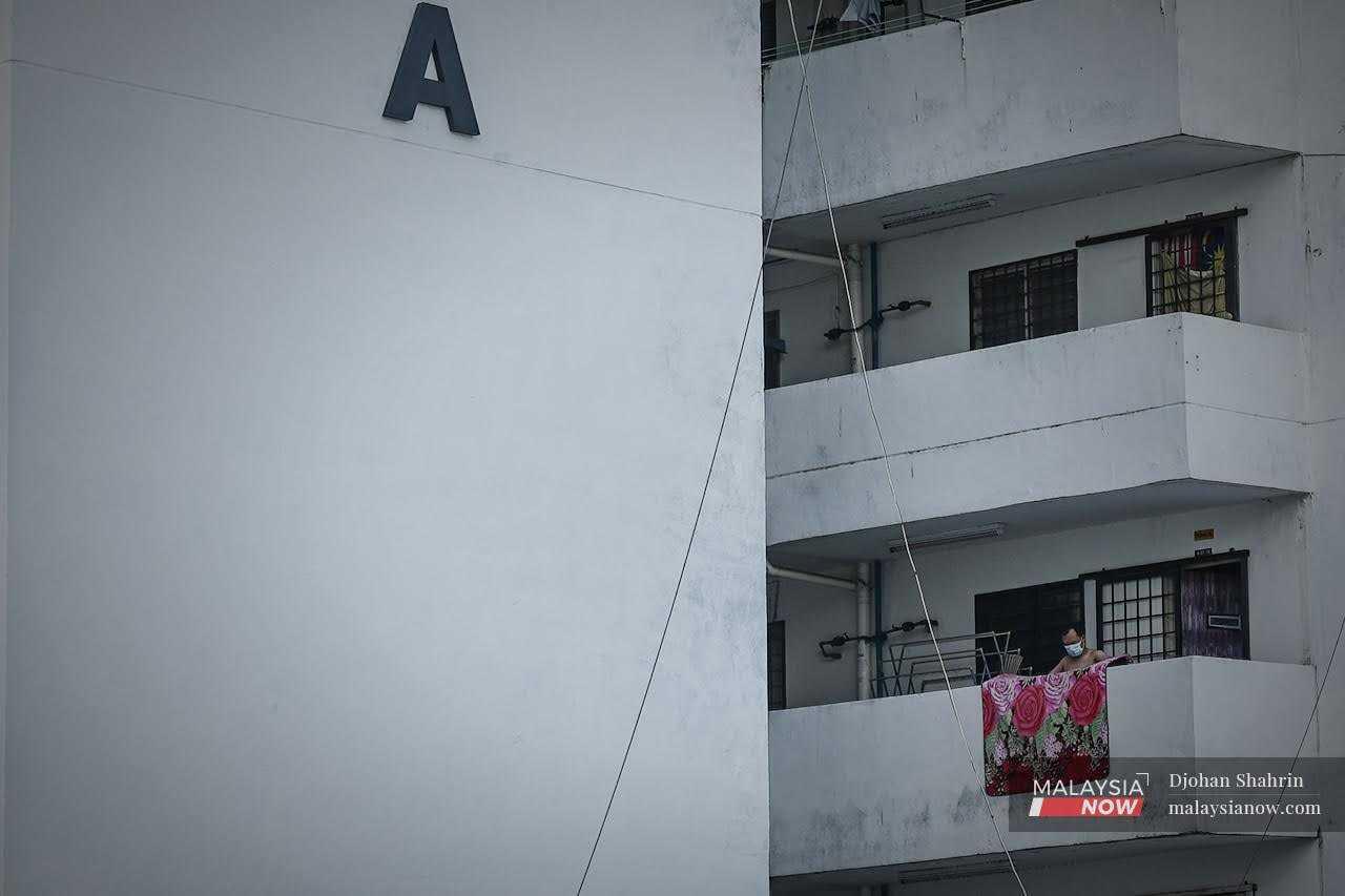 Seorang penduduk menggantung permaidani untuk dikeringkan di balkoni rumahnya di unit perumahan kos rendah di Kuala Lumpur.