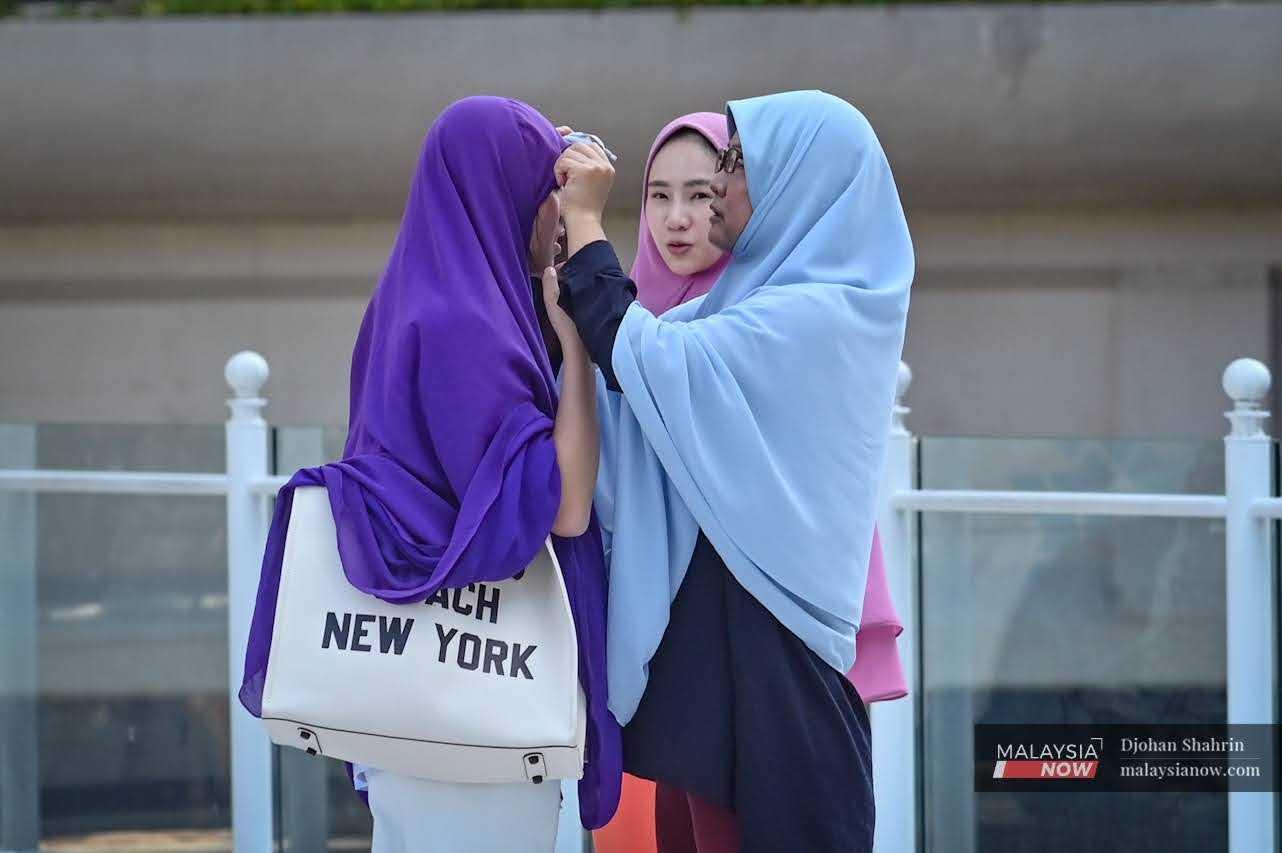 Gelagat pelancong dari Jepun membetulkan tudung semasa memasuki kawasan Masjid Jamek pada 16 Februari.
