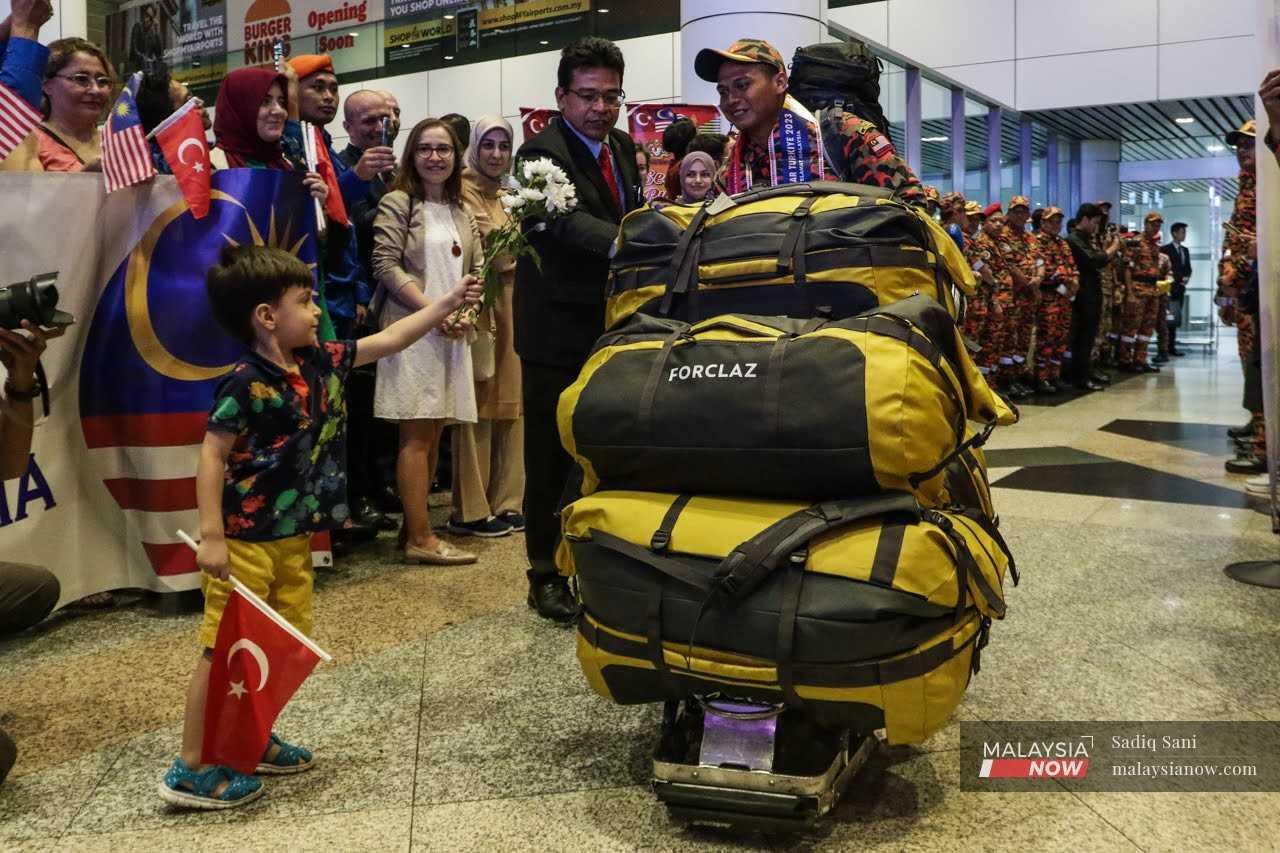 Seorang kanak-kanak menghadiahkan sejambak bunga kepada anggota mencari dan menyelamat Malaysia yang baru tiba dari misi SAR gempa bumi di Turkiye.