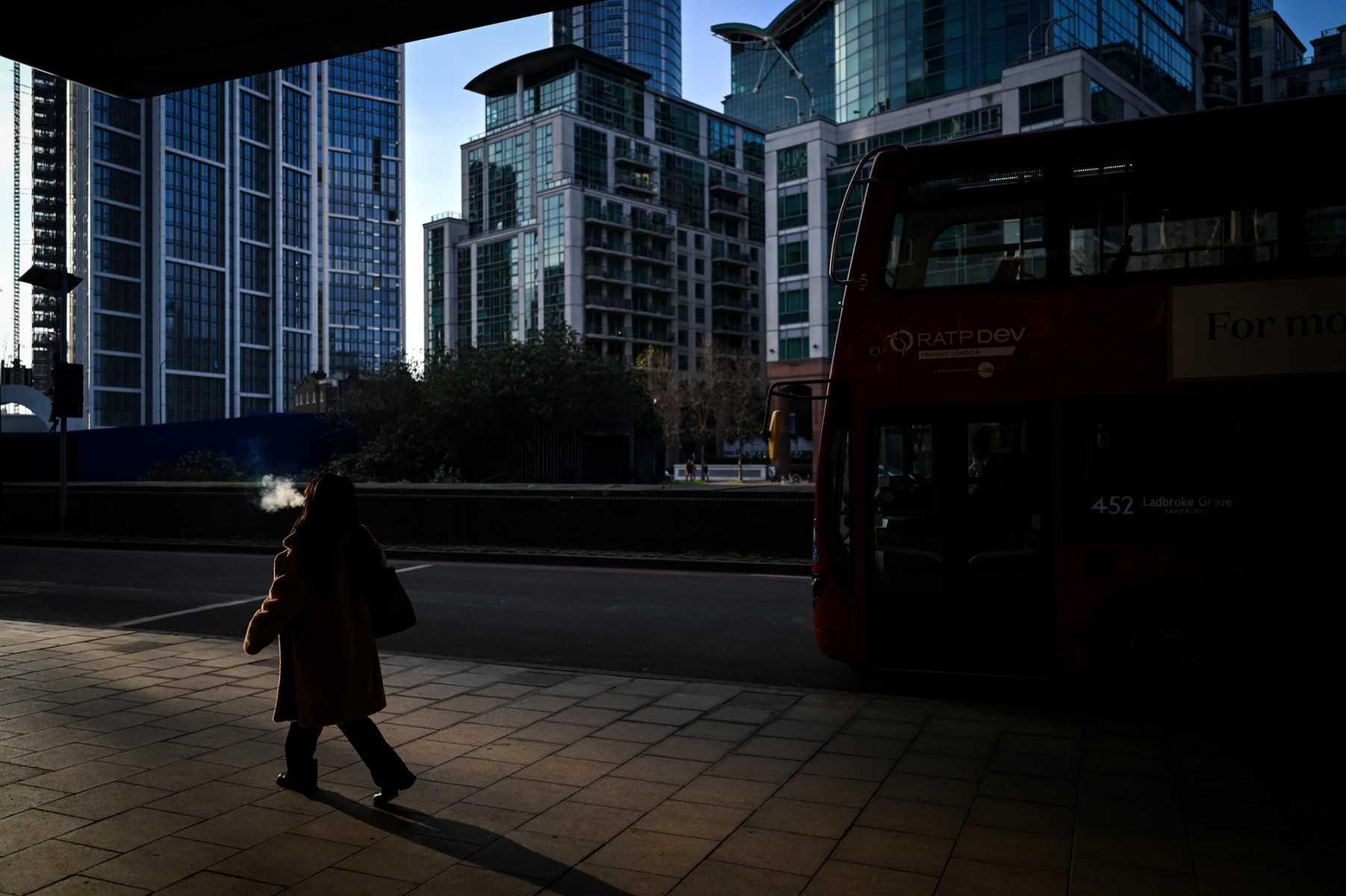 A commuter blows out smoke while walking on the sunlight towards the Vauxhall bus station in central London, on Jan 24. Photo: AFP