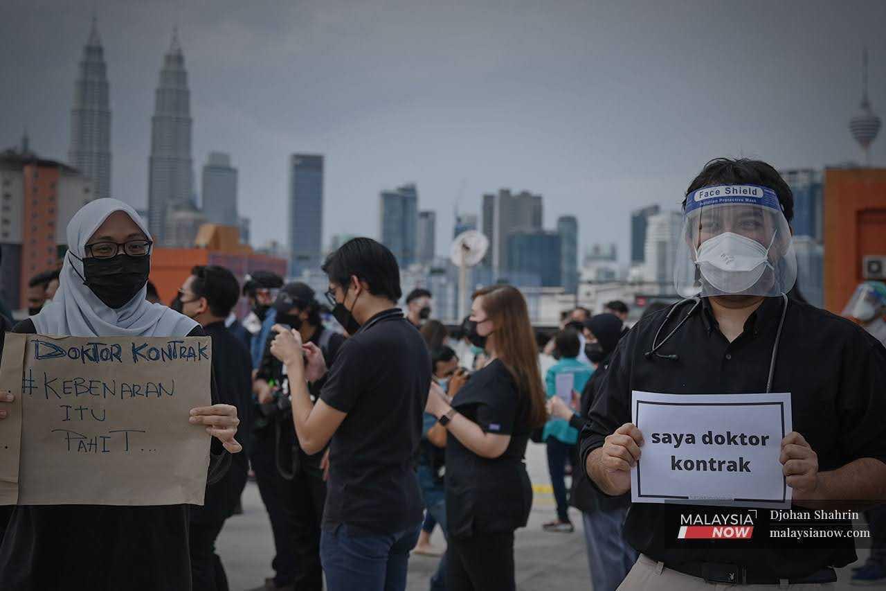 Contract doctors at Hospital Kuala Lumpur hold up placards during a walkout in 2021.