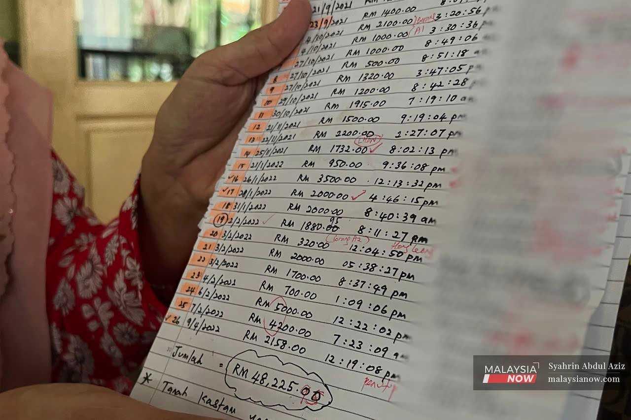 A teacher holds up a piece of paper showing the payments she made to a woman accused of swindling people out of hundreds of thousands of ringgit in a property scam in Taiping, Perak.