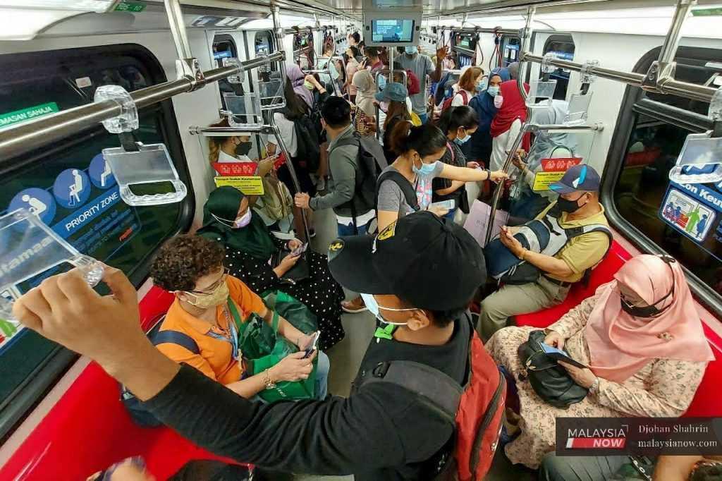 Passengers wearing face masks use their mobile phones in an LRT in Kuala Lumpur.