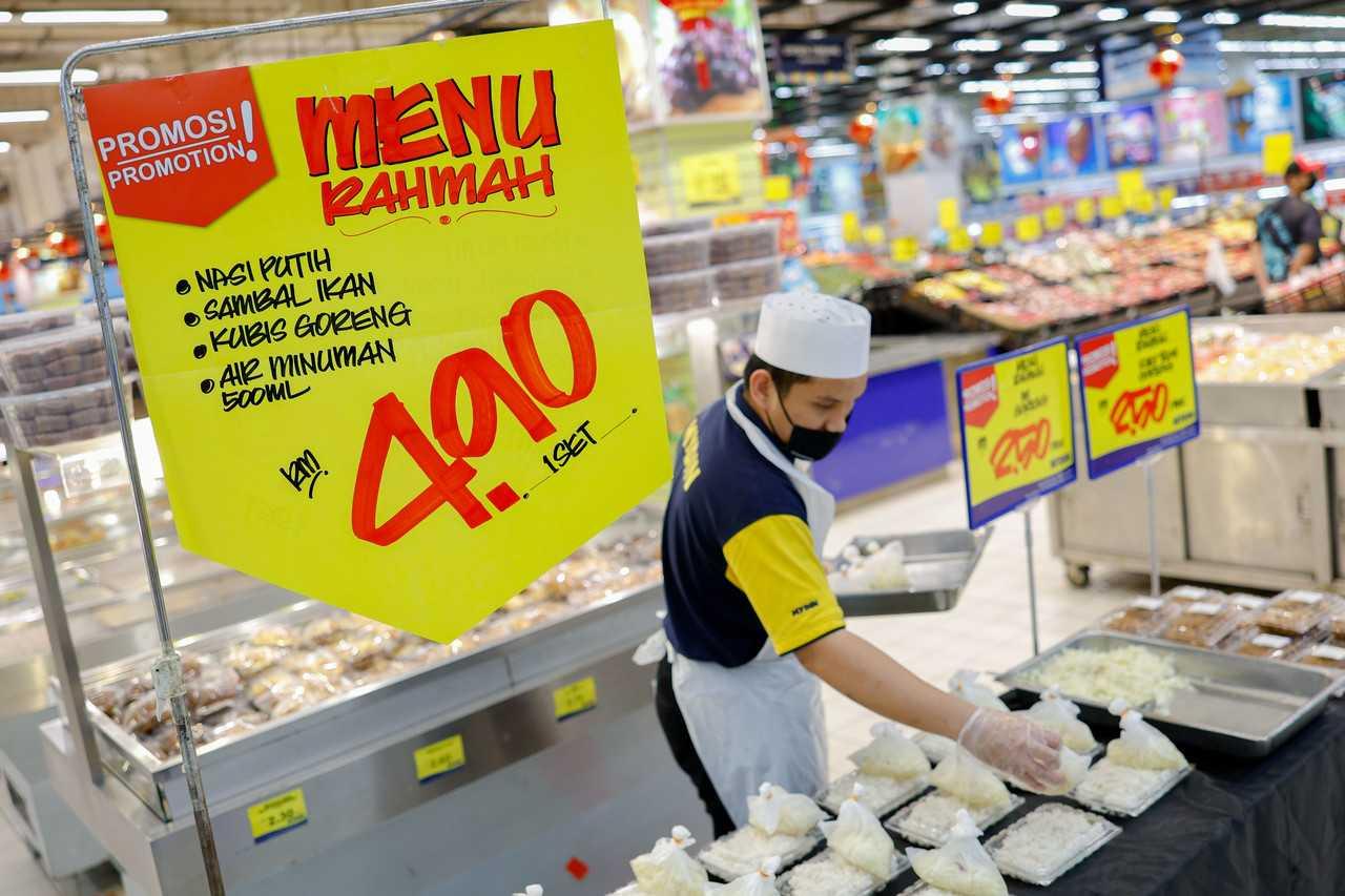 A worker arranges containers containing food to be sold under the Menu Rahmah initiative at the Mydin hypermarket near Ayer Keroh, Melaka. Photo: Bernama