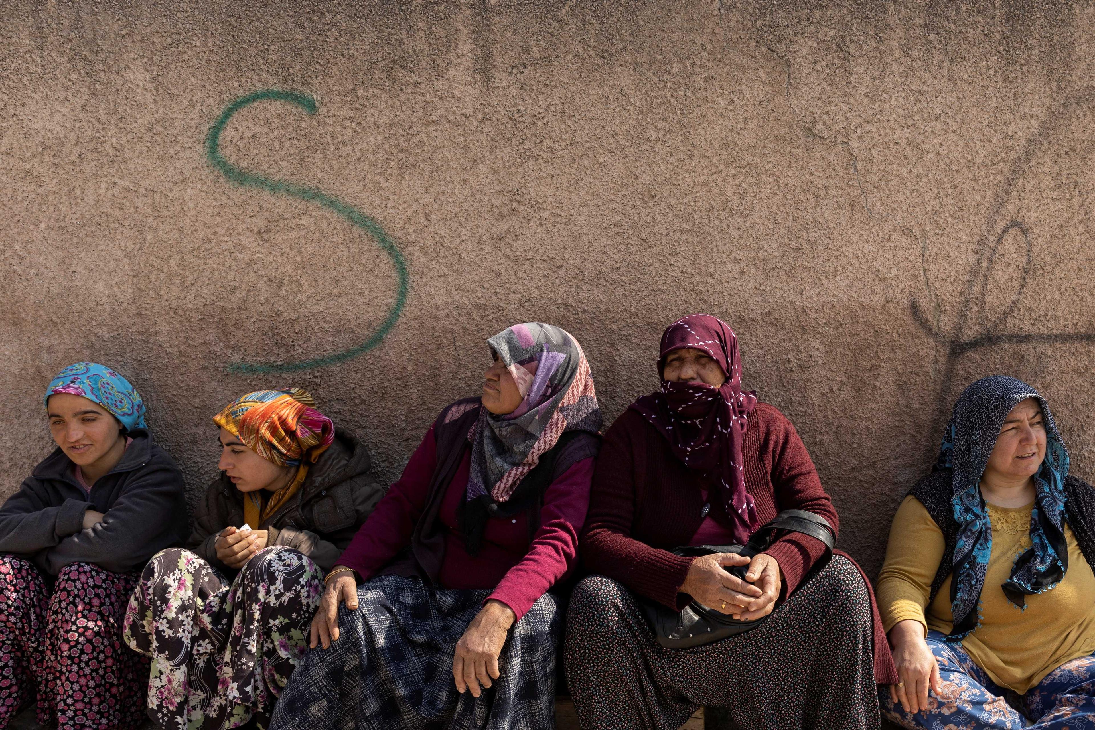 Women sit on the ground while queuing for aid, for victims of the deadly earthquake in Hatay, Turkey, Feb 24. Photo: Reuters