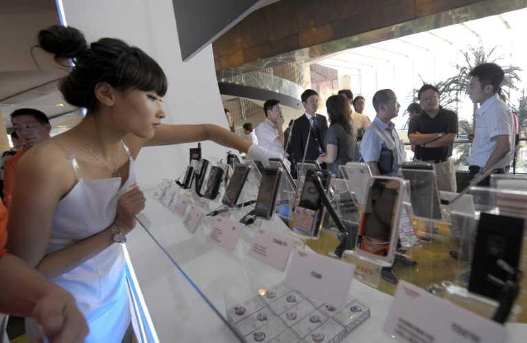 A staff from Lenovo arranges mobile phones on display prior to a launching ceremony in Beijing on Sept16, 2009. Photo: AFP